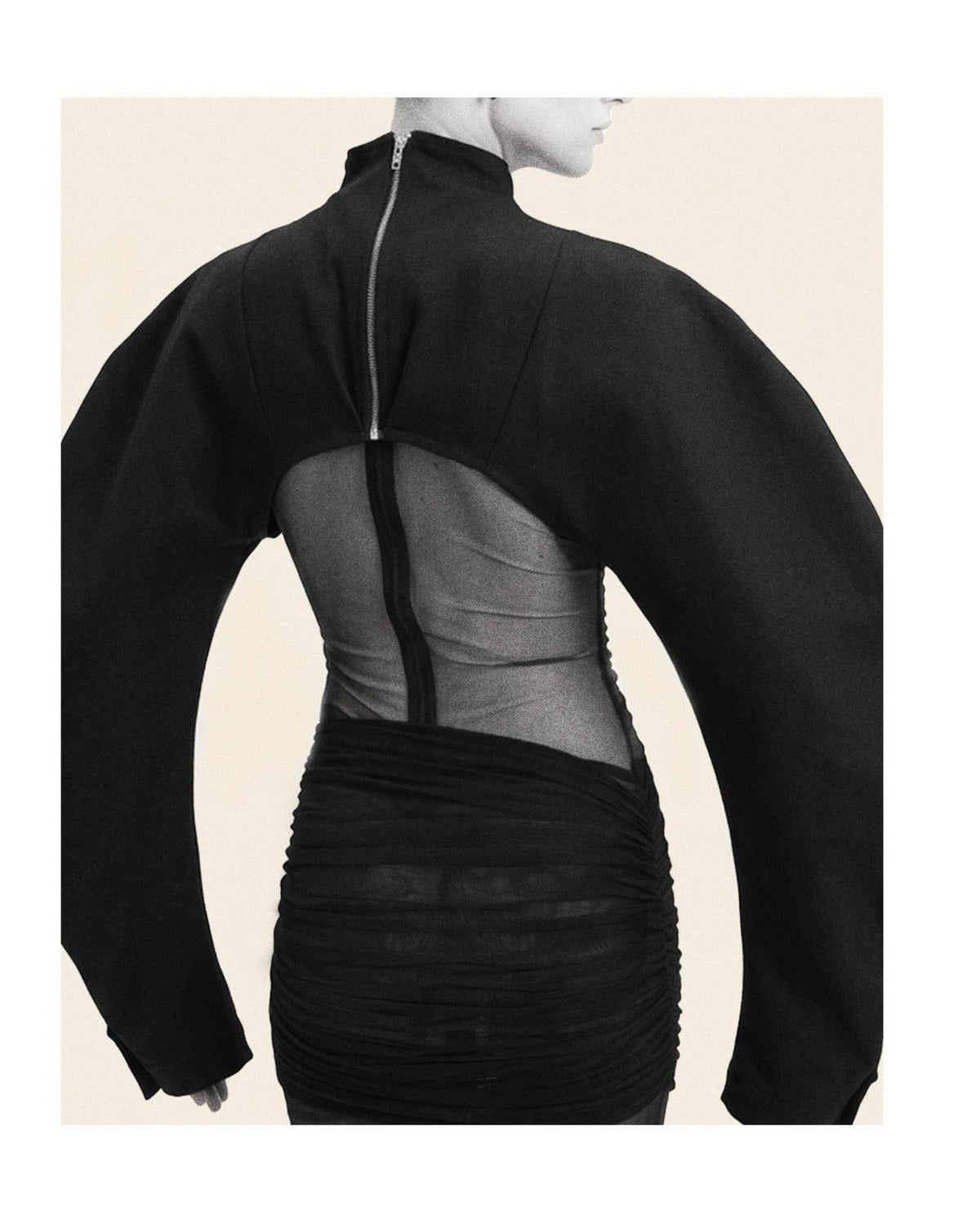 Black high-neck long-sleeve dress with a sheer back panel and a central zipper, shown on a mannequin from the back against a light beige background.